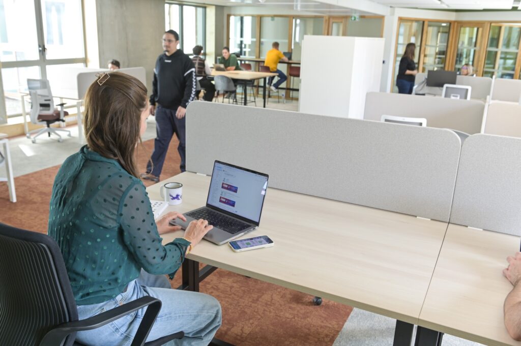 Un poste de coworking derrière sa cloison acoustique, ordinateur ouvert